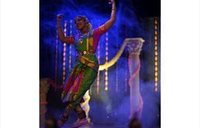 A female dancer, dances on a stage dressed in an indian Bharatanatyam costume (pleated saree).